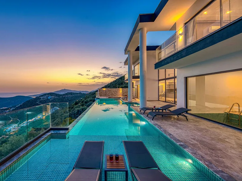 Piscine à débordement face à la mer au coucher du soleil, terrasse d'une villa contemporaine
