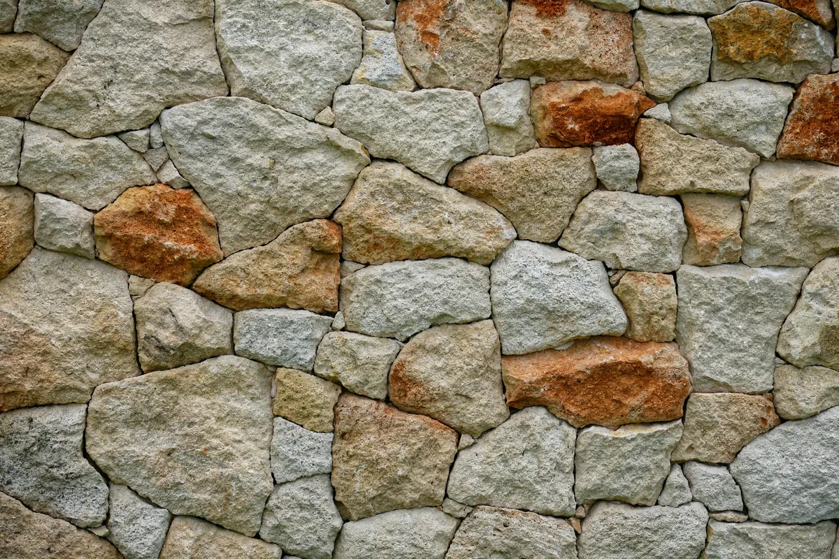 Détail d'un mur en pierre sèche ancienne sous lumière rasante chaude