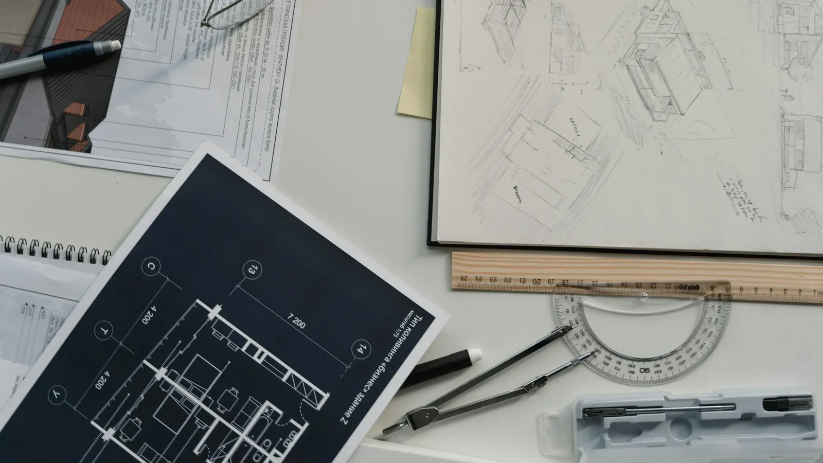 Plans d'architecte et croquis disposés avec règle et compas sur un plan de travail clair